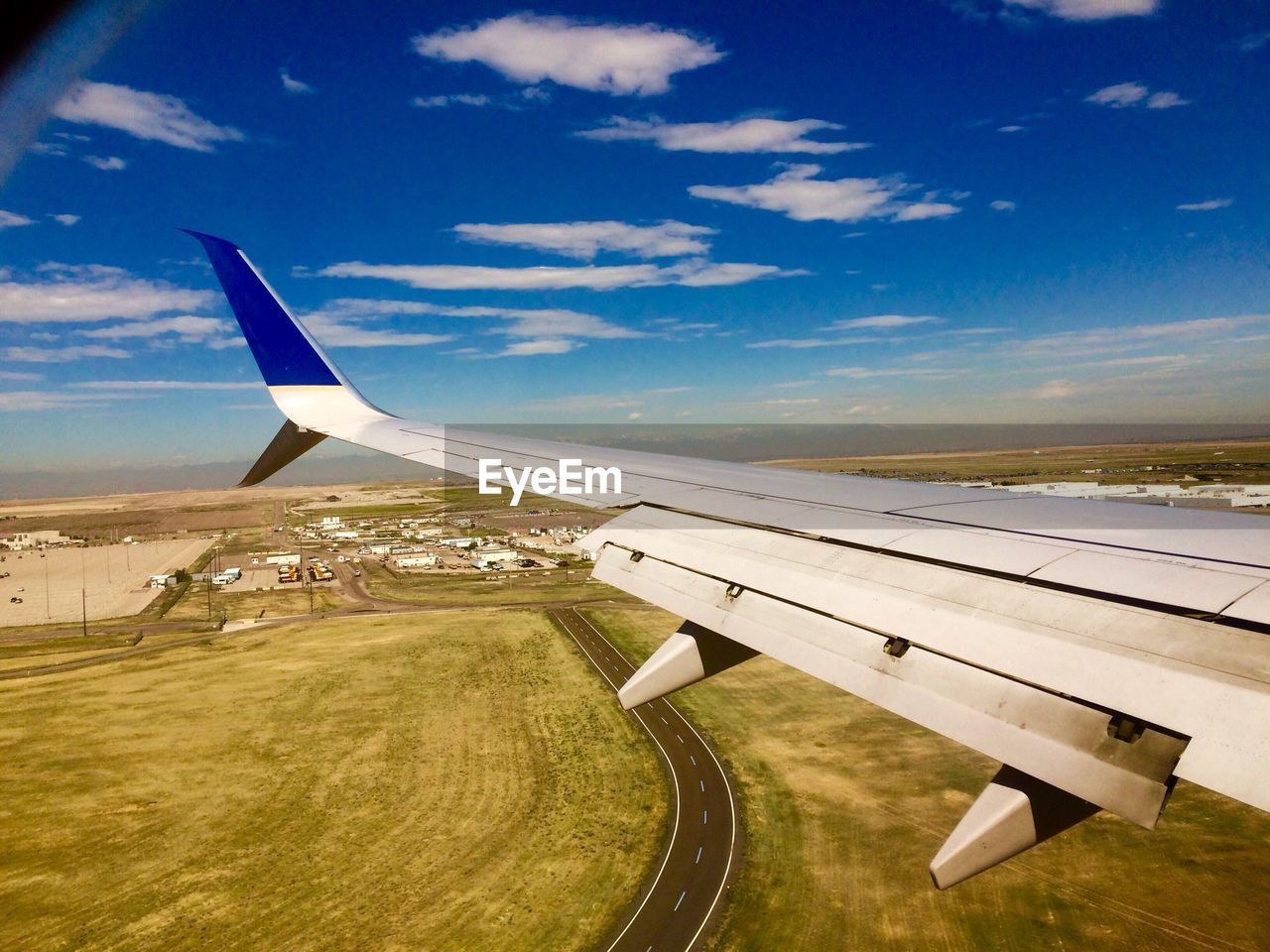 CROPPED IMAGE OF AIRPLANE WING OVER LANDSCAPE