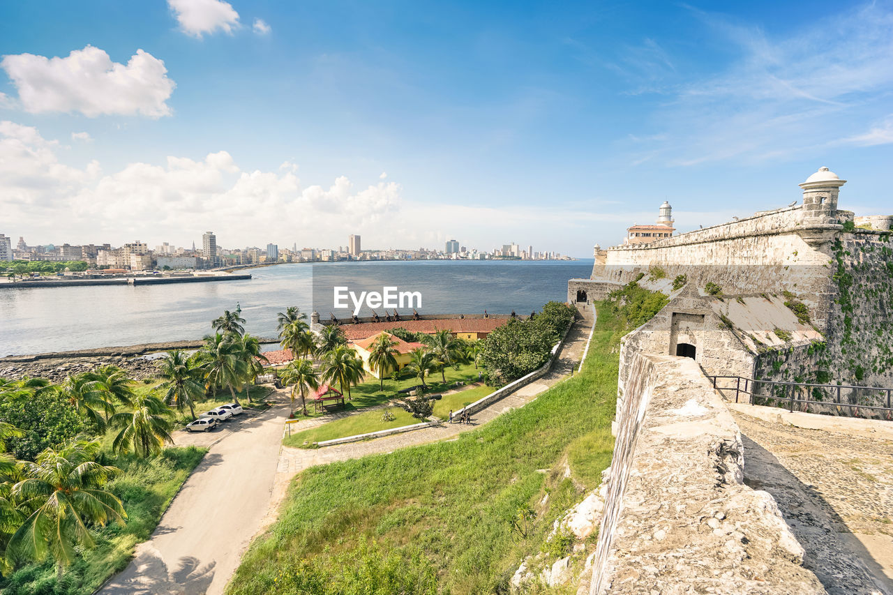 Fort by river against blue sky in city during sunny day