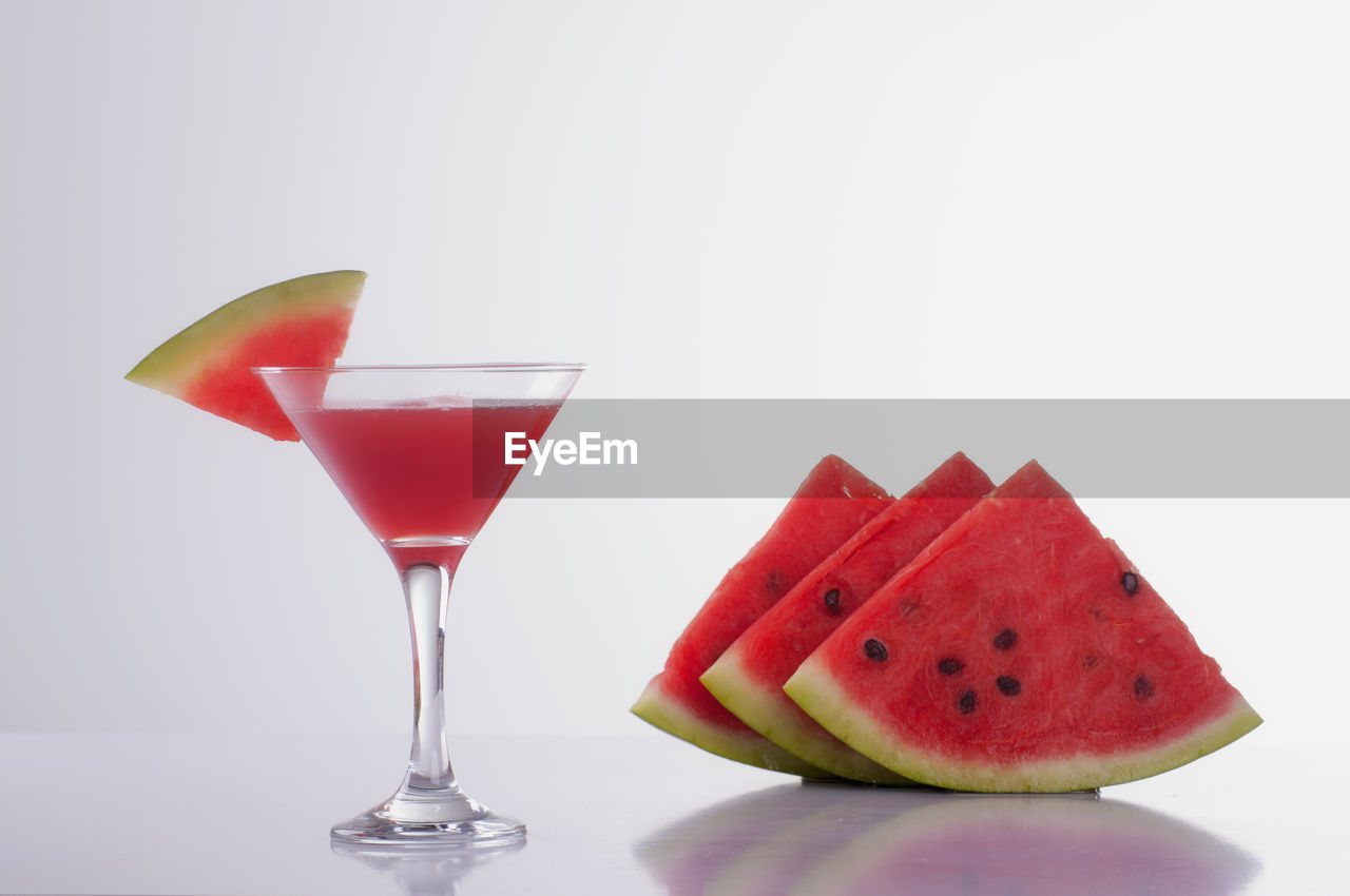 Watermelon slices and cocktail glass against white background