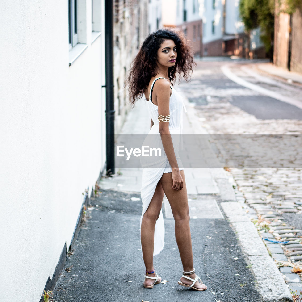 Portrait of young woman standing on footpath