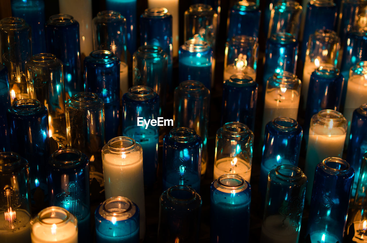 Illuminated burning tea lights at church in dark