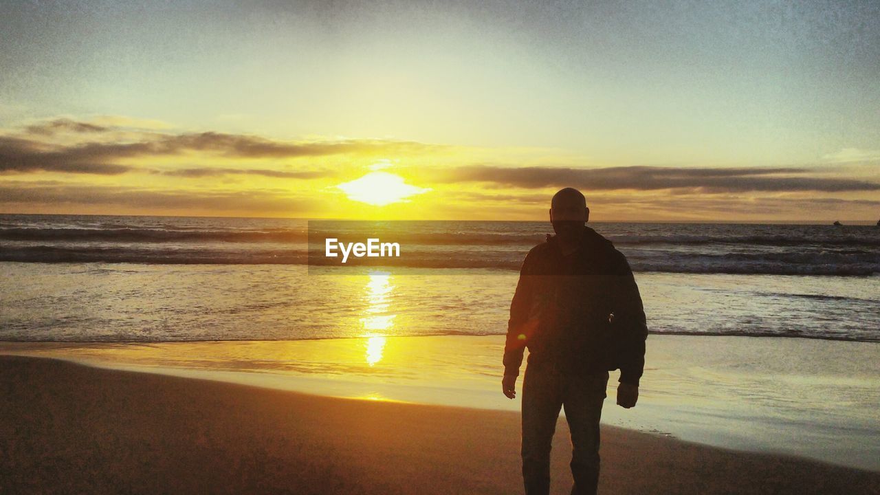 Man standing at beach during sunset