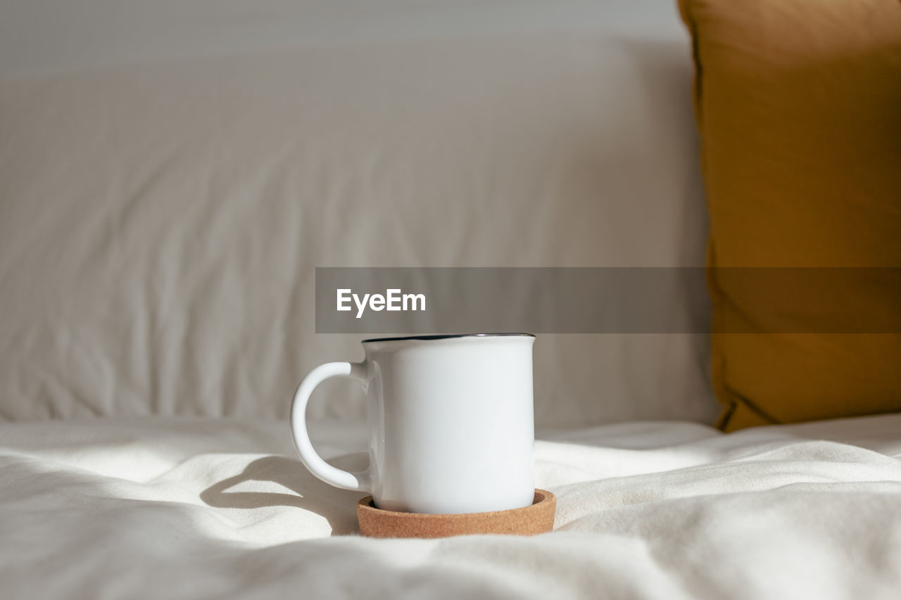 close-up of coffee cup on bed at home