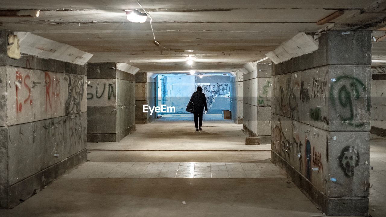 FULL LENGTH REAR VIEW OF WOMAN WALKING IN TUNNEL