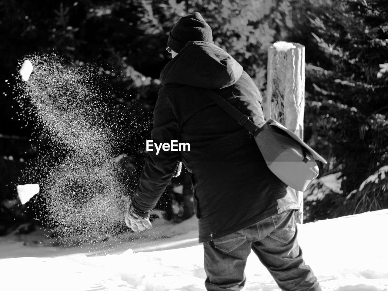 Rear view of man playing with snow