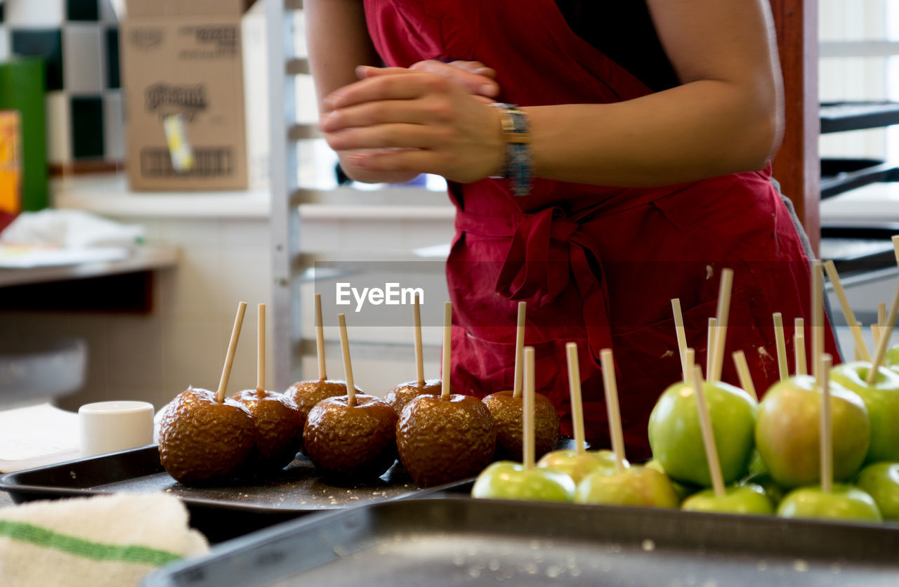 Midsection of woman preparing taffy apples in kitchen