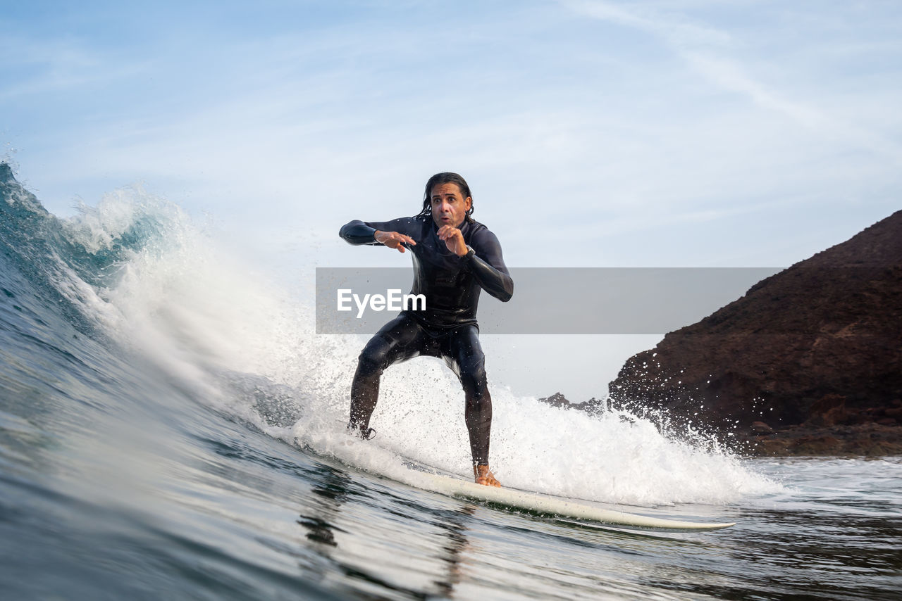 Full length of man surfing on sea against sky
