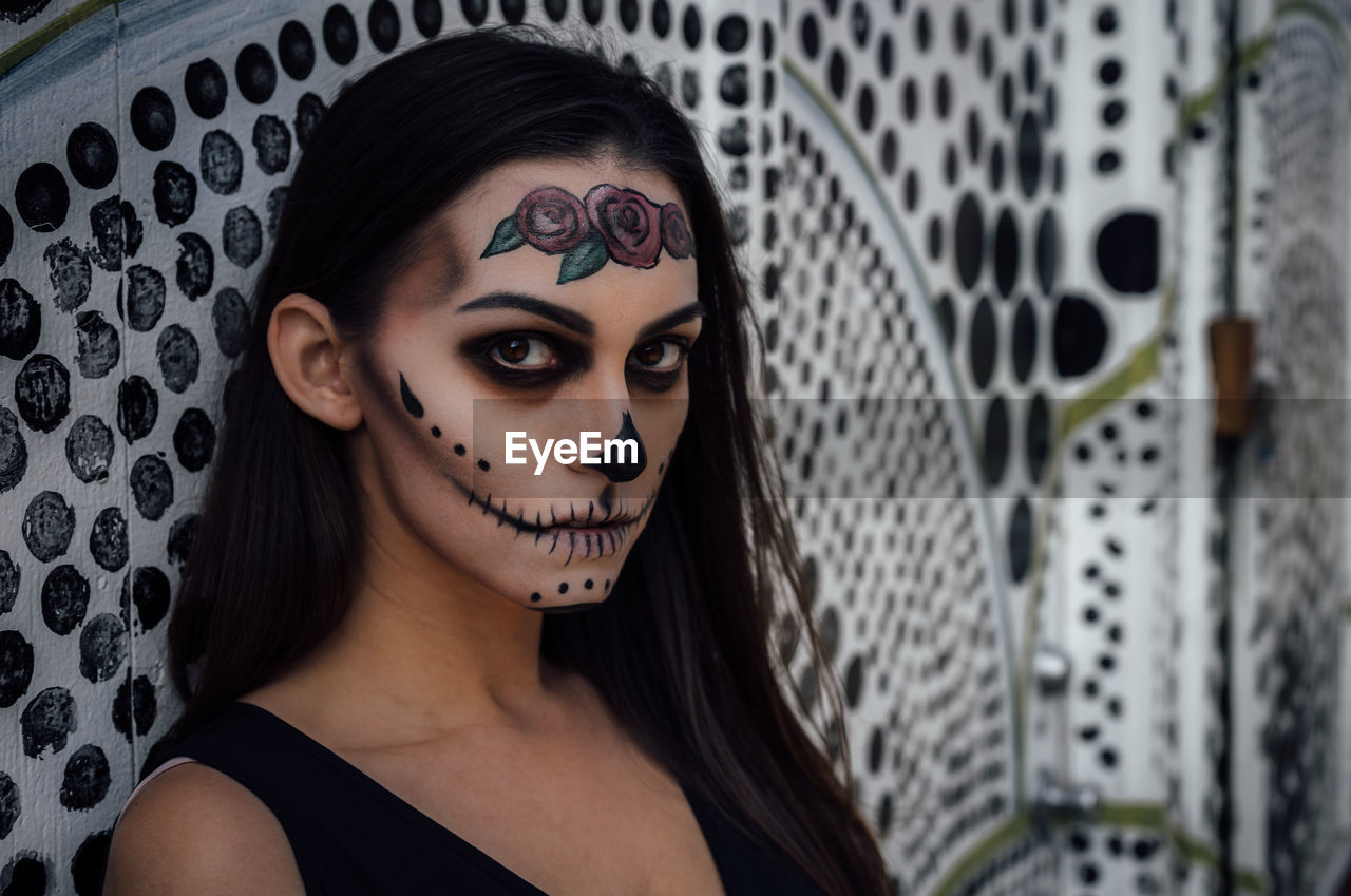 Close-up portrait of woman with spooky halloween make-up against wall