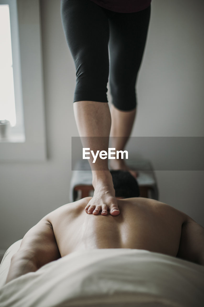 Massage therapist uses ashiatsu technique to work on patient's back