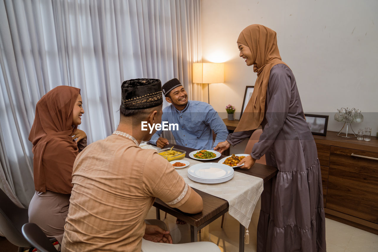 Smiling woman serving food to guests at home