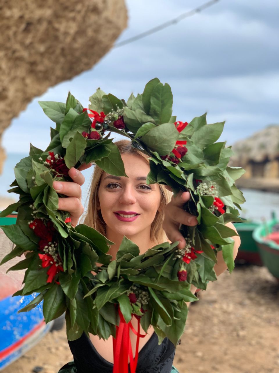 Portrait of woman holding wreath while standing on sand