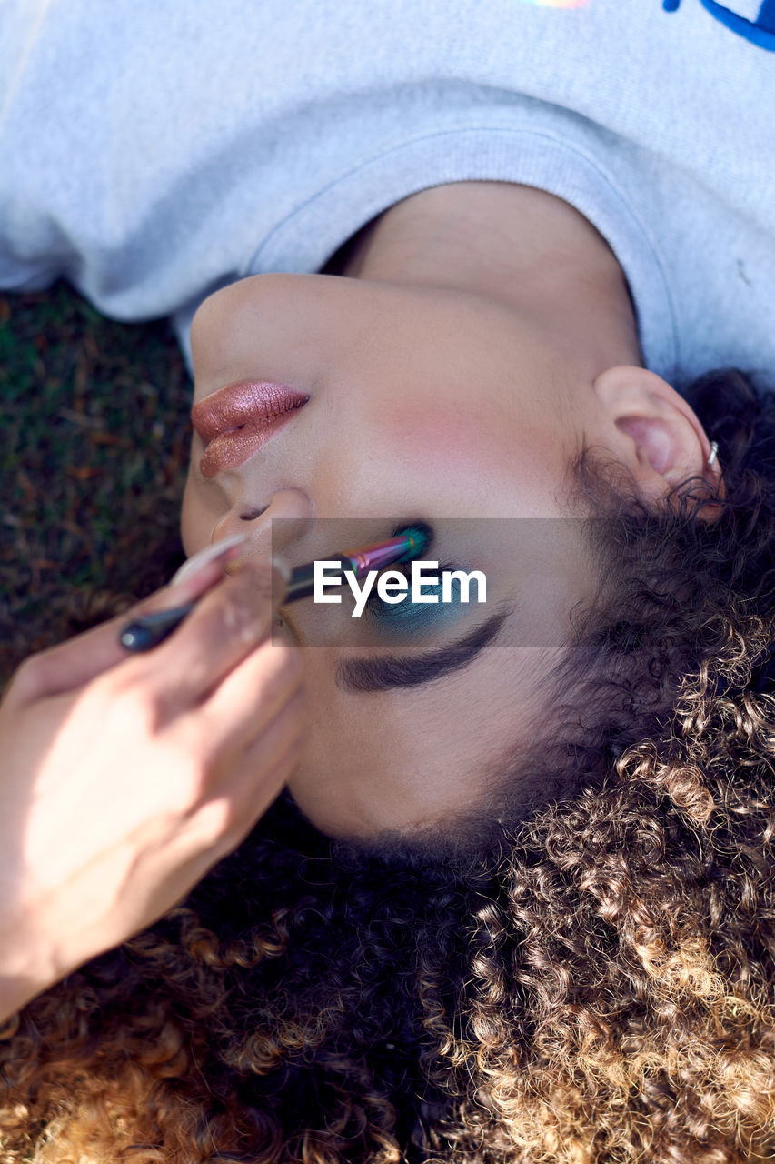 Woman with curly hair applying eyeshadow