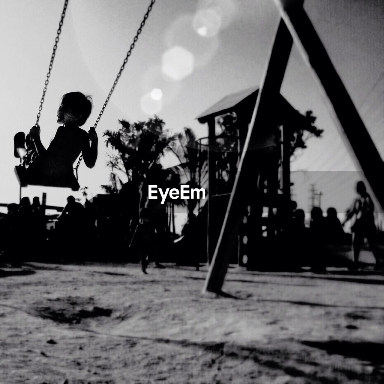 Silhouette child on swing in park