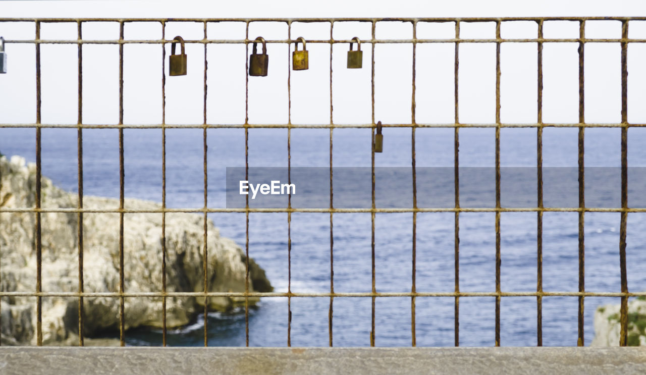 Love locks hanging to fence against sea at santa maria di leuca