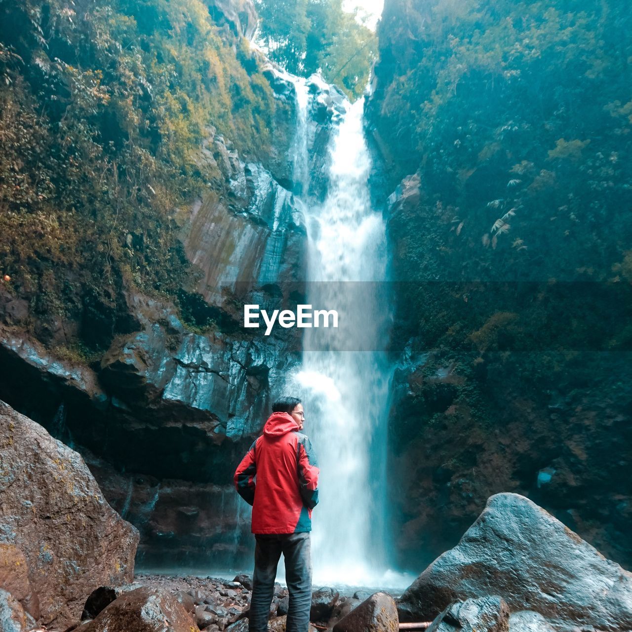 Rear view of man standing against waterfall