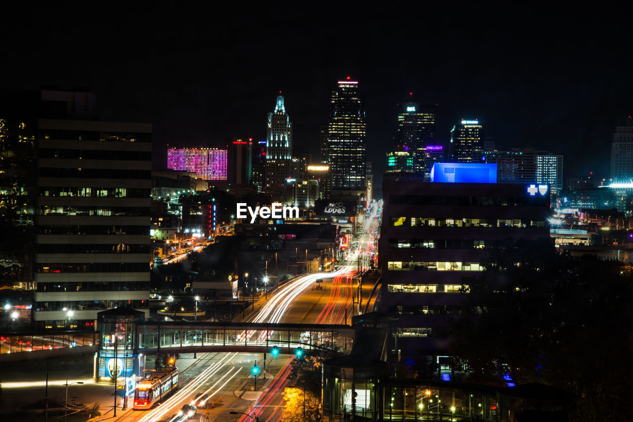 Illuminated modern buildings in city against sky at night