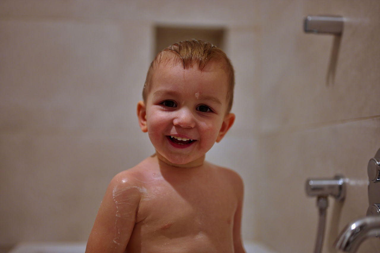 Cute little toddler having shower in bathtub