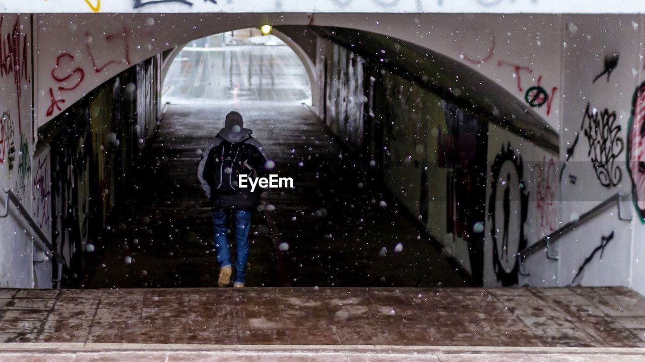 Rear view of man moving down steps towards tunnel