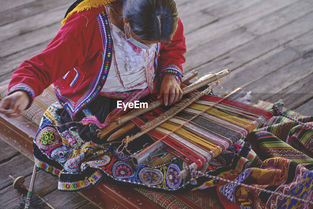 Indigenous woman showing traditional weaving technique and textile making in the andes mountain 