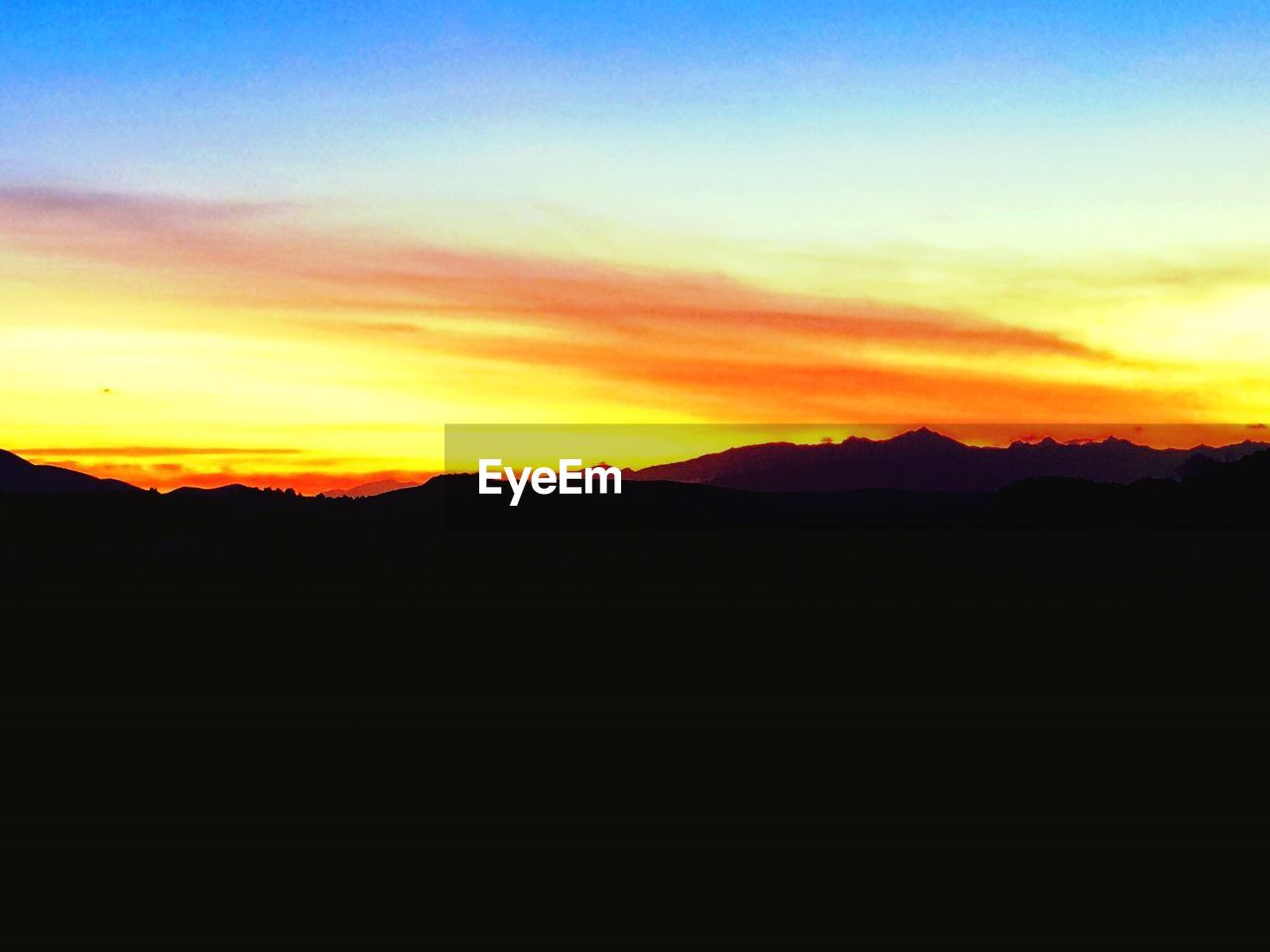 SCENIC VIEW OF SILHOUETTE MOUNTAIN AGAINST SKY AT SUNSET