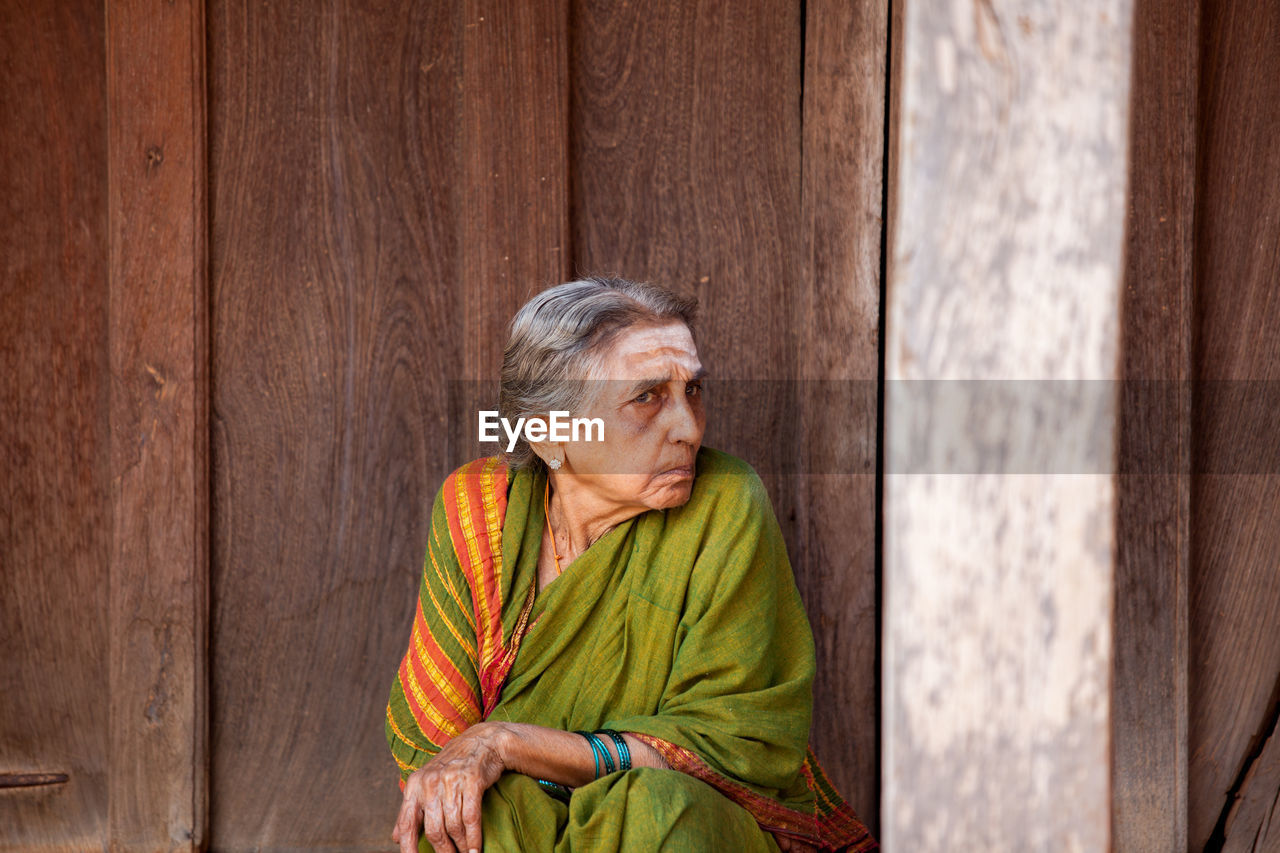 WOMAN SITTING ON WOODEN WALL