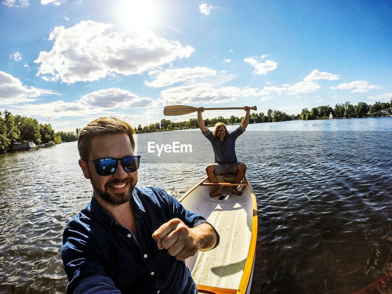 Portrait of male friends in boat on lake against sky