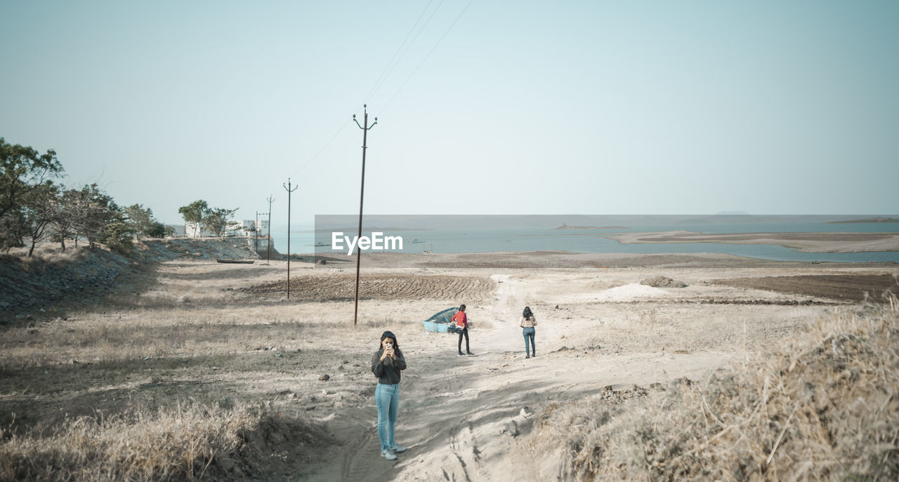 PEOPLE WALKING ON ROAD AGAINST SKY