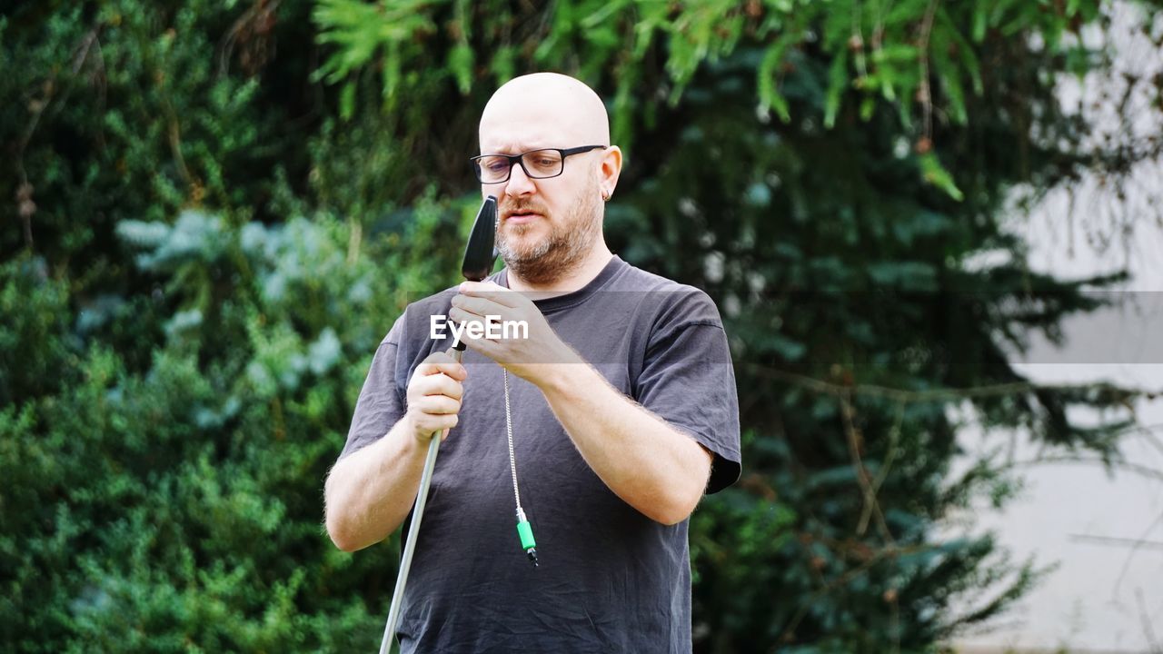 Man adjusting fishing rod against trees