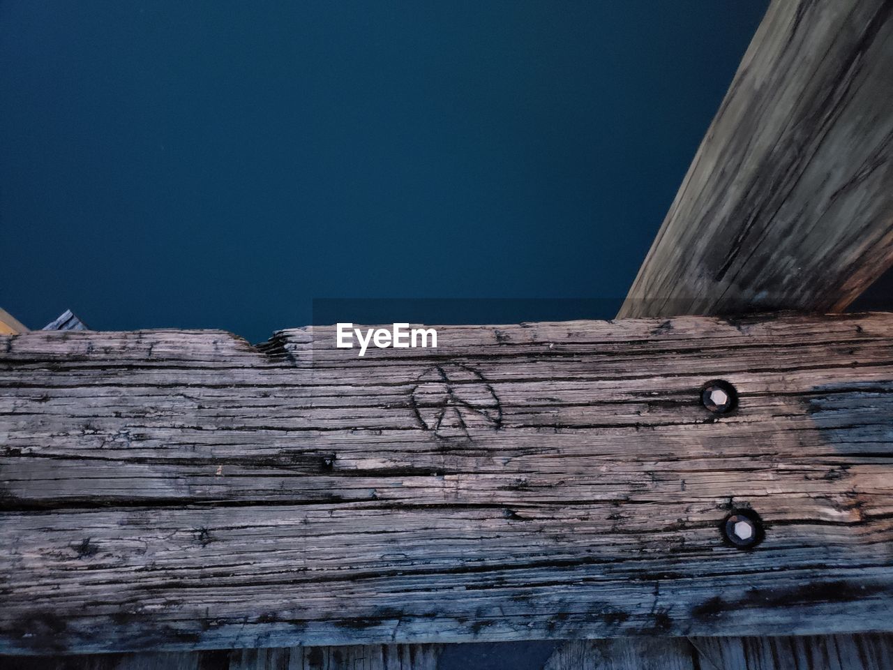 LOW ANGLE VIEW OF WEATHERED WOOD AGAINST BLUE SKY