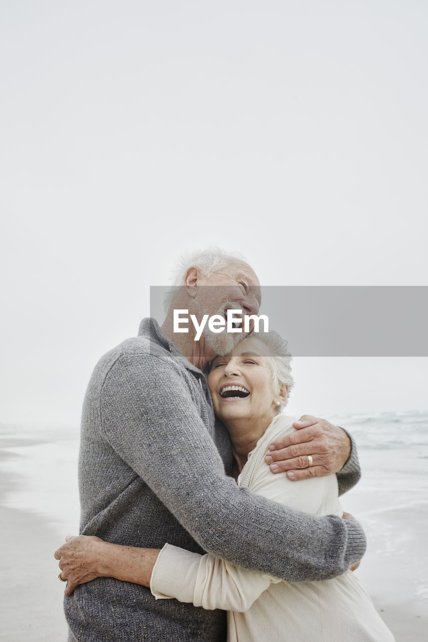 Laughing senior couple embracing at the sea