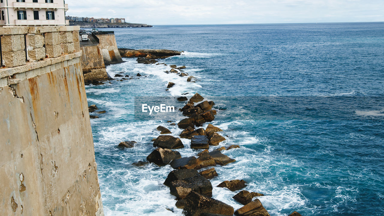 Waves of ocean crashing in rocks in syracusa city in sicily