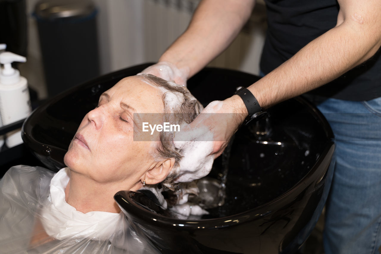 An elderly woman washes her hair in a beauty salon