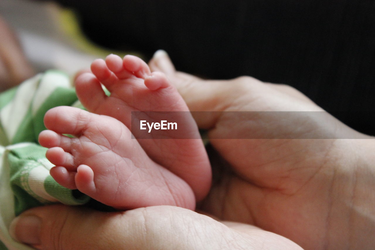 Cropped hands of mother touching feet of baby