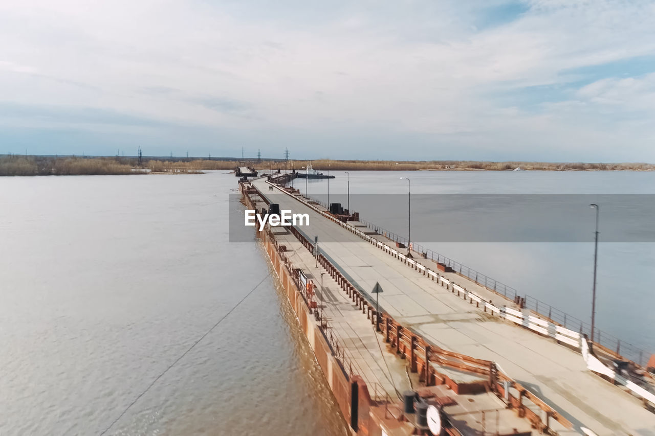 HIGH ANGLE VIEW OF BRIDGE AND SEA AGAINST SKY