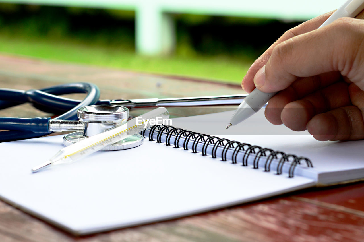 Cropped image of doctor writing in book at desk