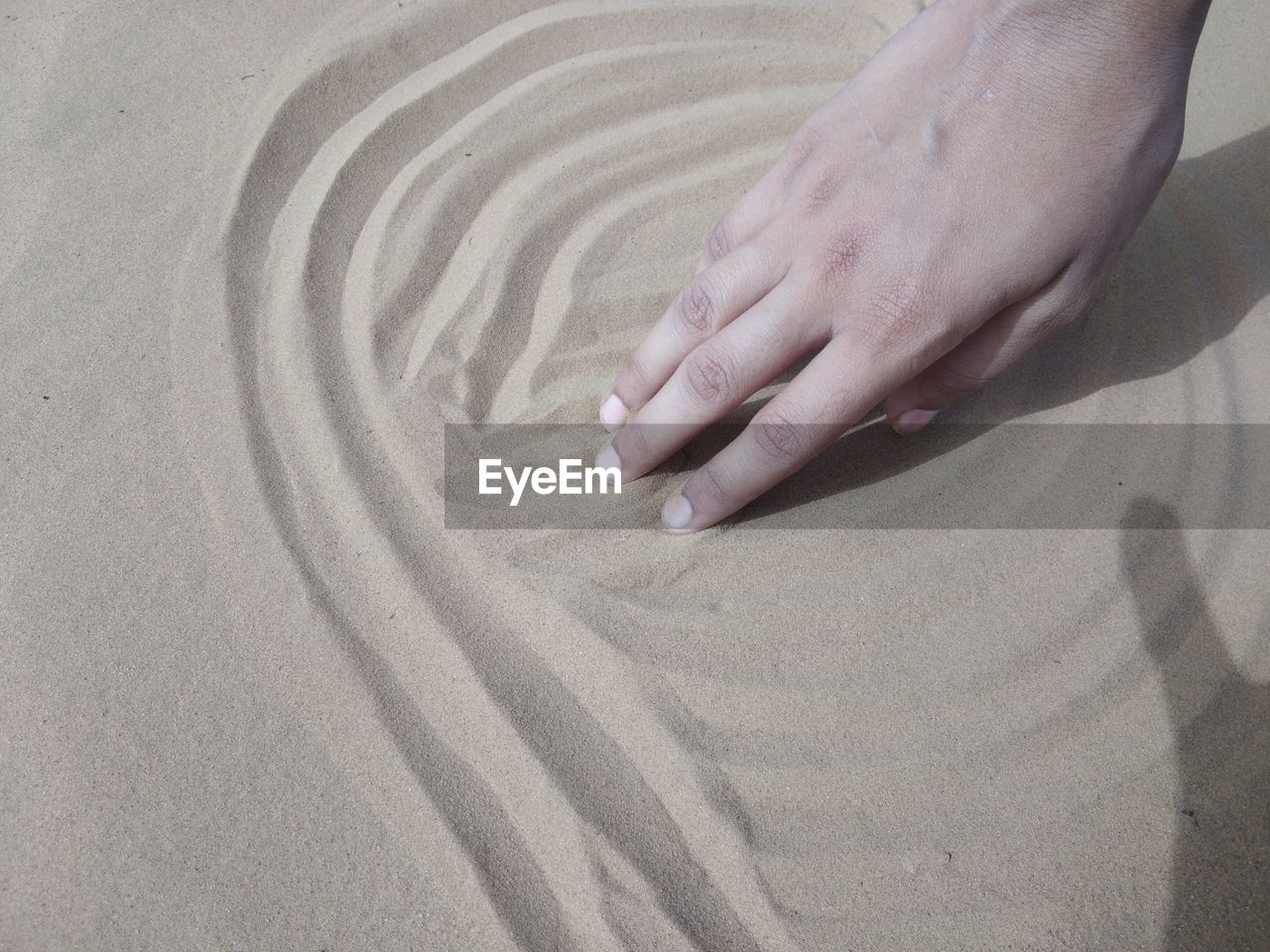 HIGH ANGLE VIEW OF WOMAN HANDS ON SAND