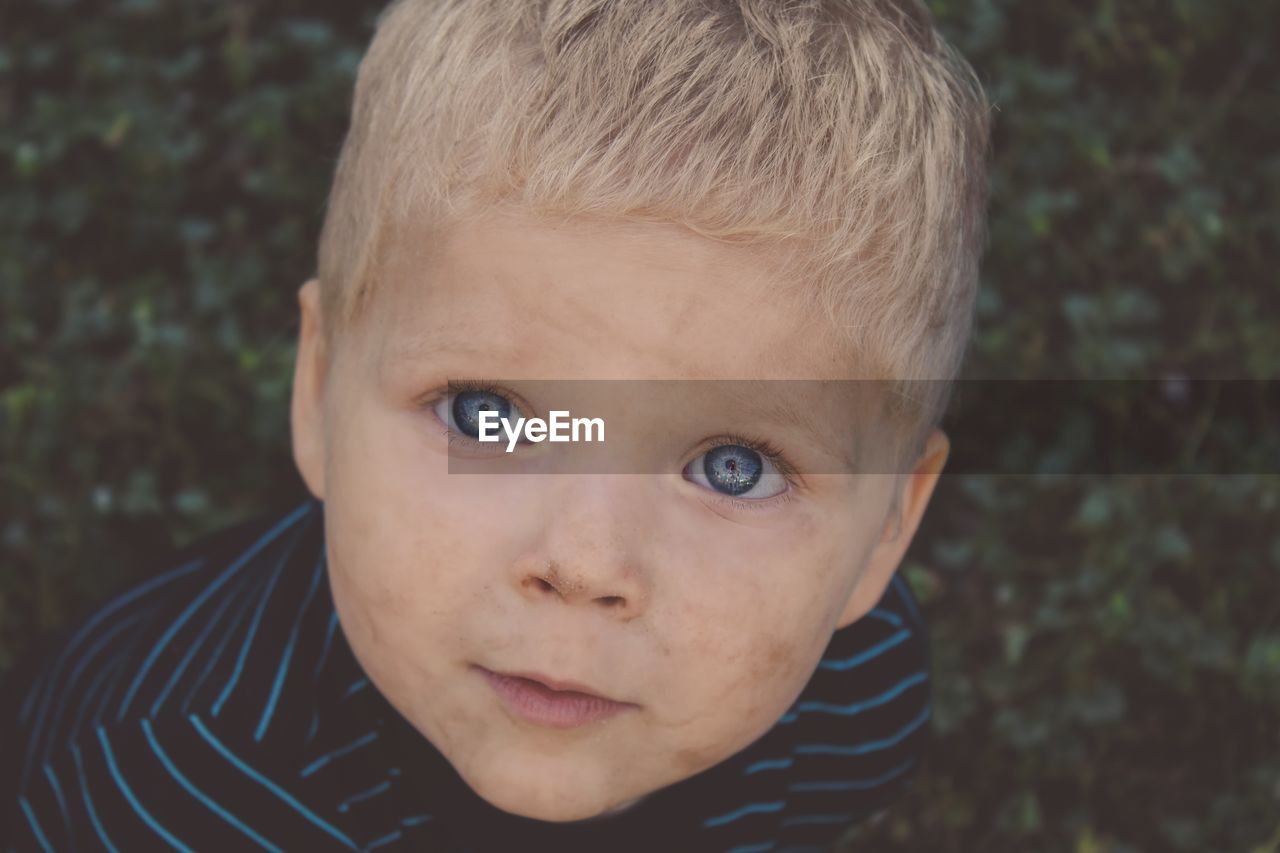 Close-up high angle portrait of cute baby boy with messy face and gray eyes outdoors