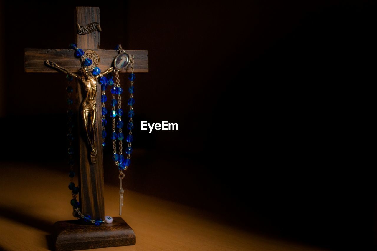 LOW ANGLE VIEW OF CROSS HANGING AGAINST WALL