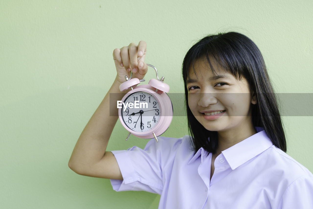 PORTRAIT OF A SMILING YOUNG WOMAN HOLDING YELLOW WALL