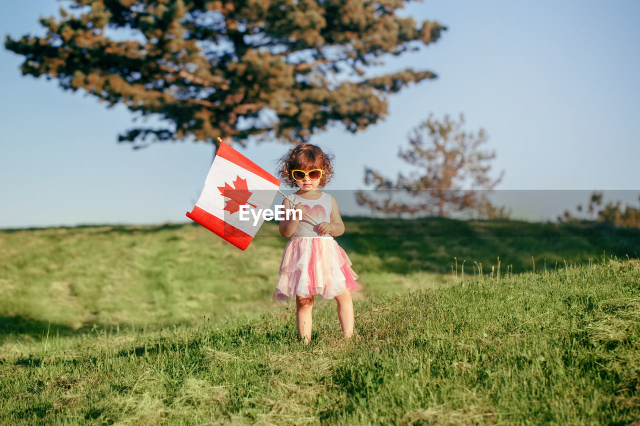 Girl holding canadian flag standing on land