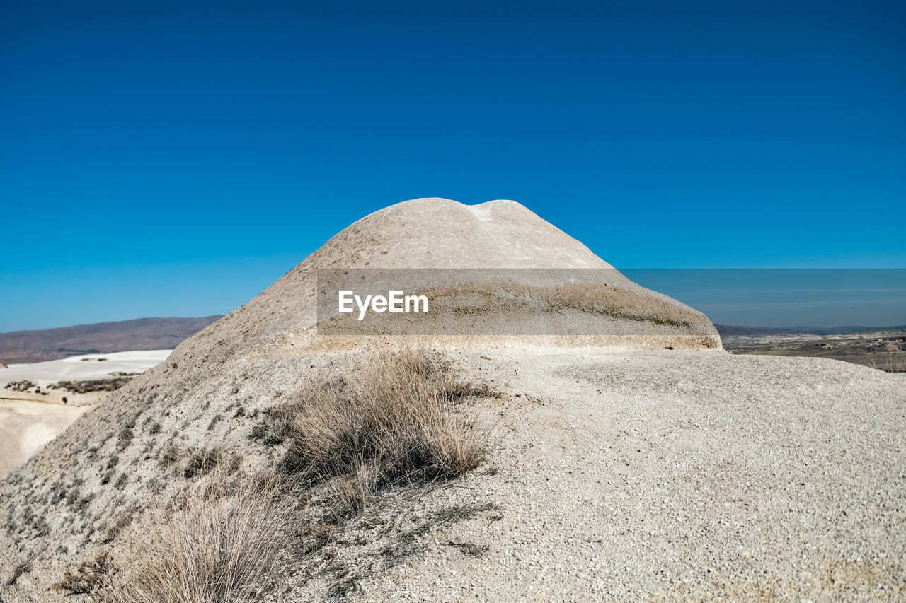 Low angle view of rock formation against clear blue sky