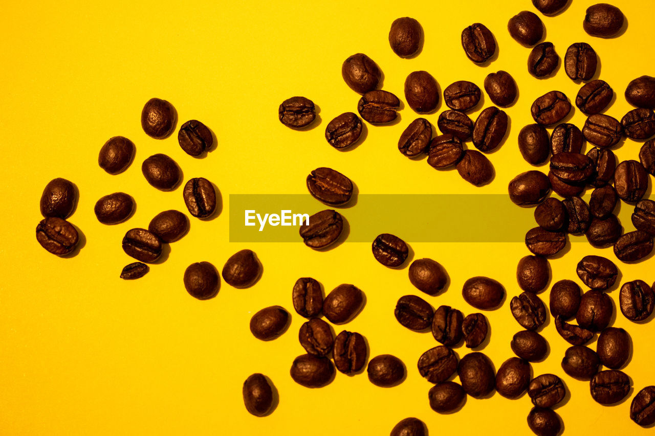 CLOSE-UP OF COFFEE BEANS AGAINST YELLOW BACKGROUND