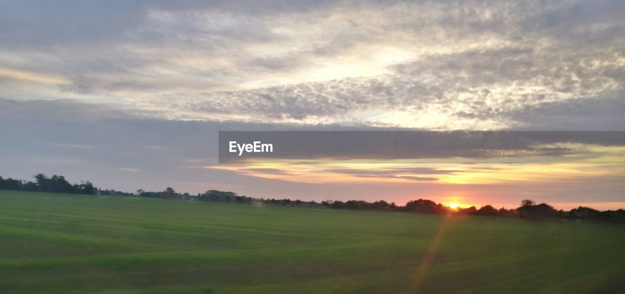 SCENIC VIEW OF AGRICULTURAL FIELD AGAINST SKY DURING SUNSET