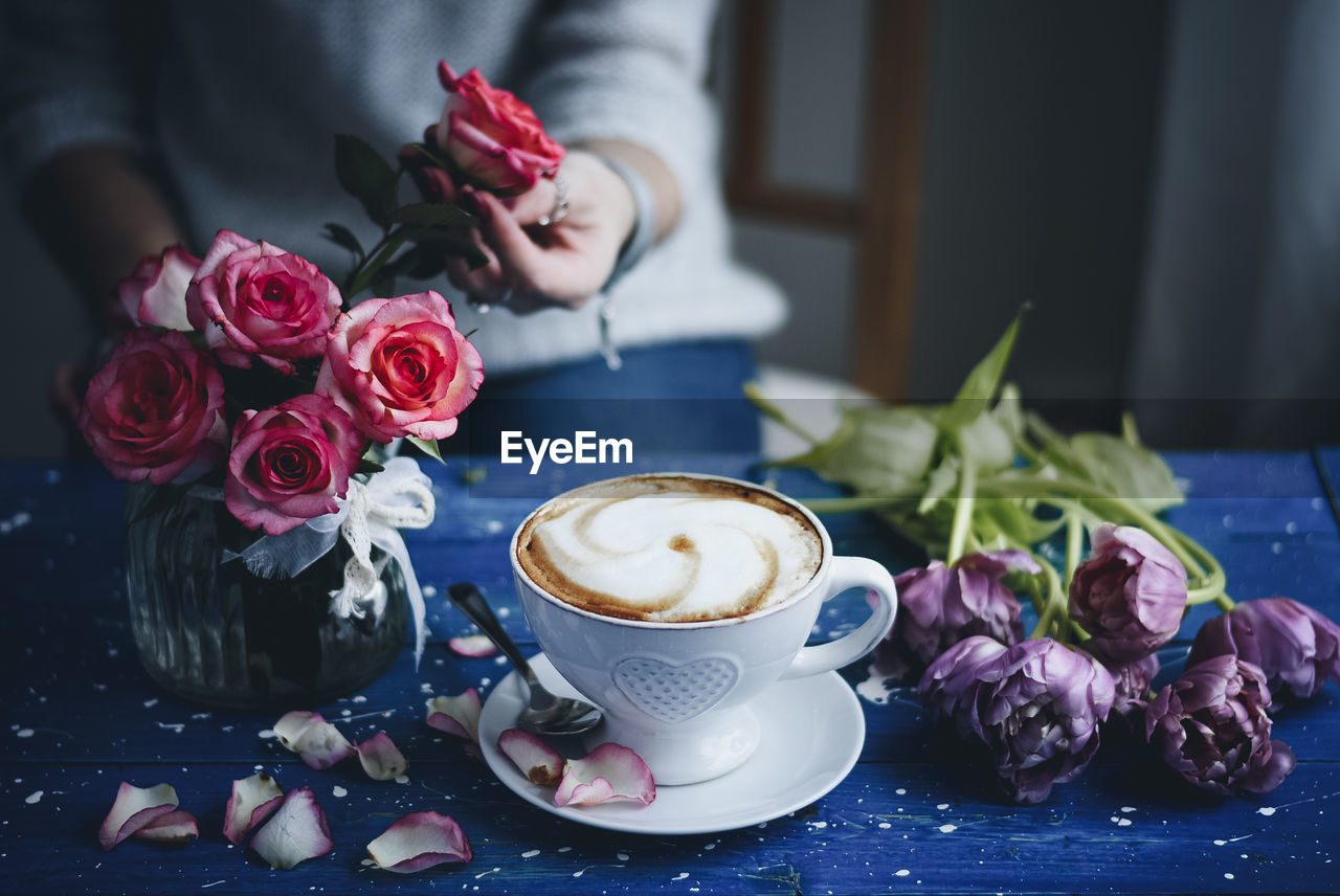 Coffee cup and roses on table