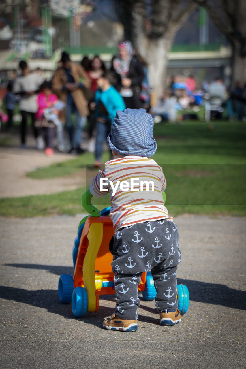 REAR VIEW OF GIRL WITH TOYS ON STREET