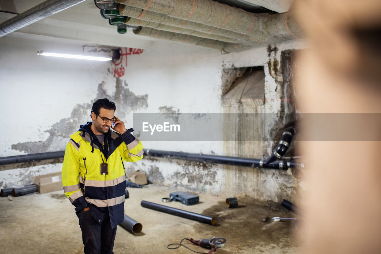 Smiling manual worker talking on phone in basement