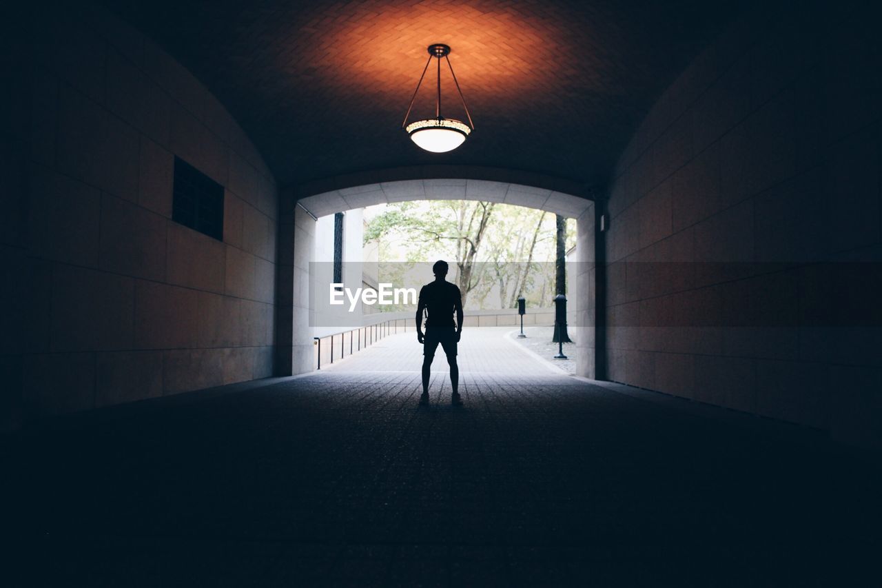 Silhouette man standing in tunnel