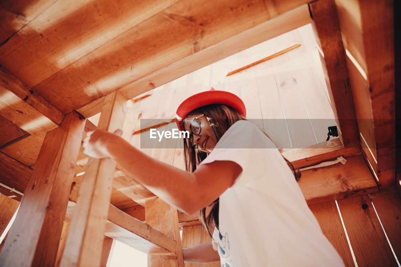 Low angle view of girl climbing wooden ladder in room