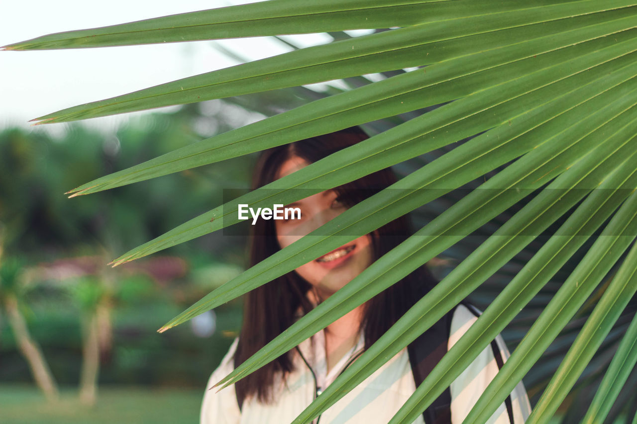 Portrait of woman amidst palm leaf outdoors