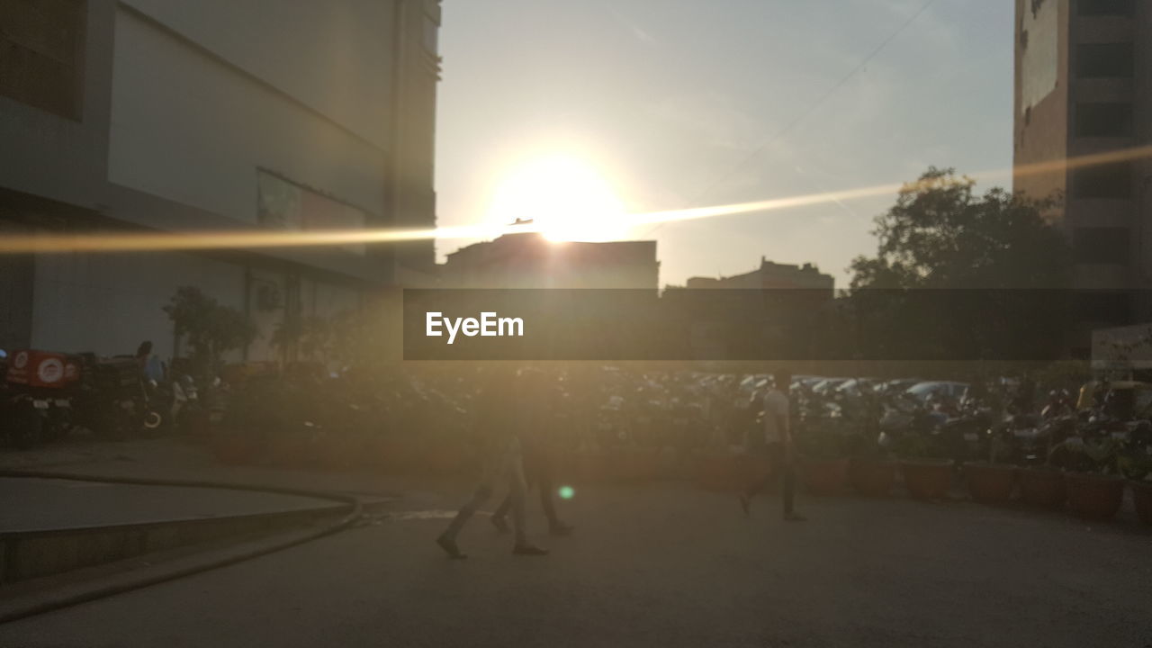 MAN ON CITY STREET AGAINST SKY DURING SUNSET